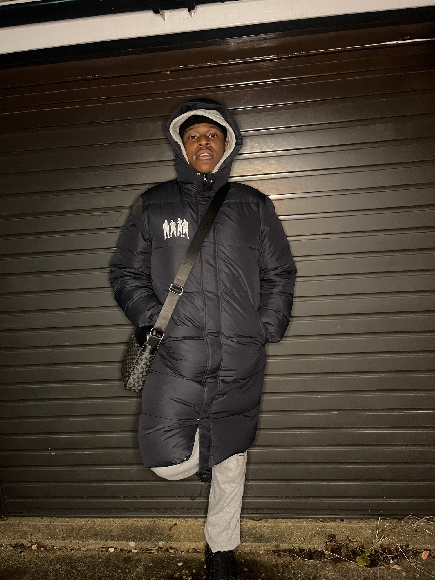 Person wearing a black puffer jacket standing against a dark background